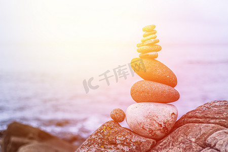 禅宗石摄影照片_平衡、放松和健康：外面的石冢，模糊背景中的海洋。