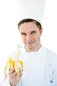 迷人的男厨师拿着香蕉对着镜头微笑