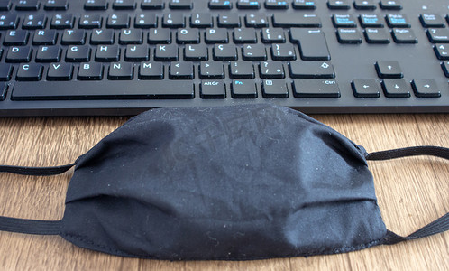 办公桌上办公室键盘旁边的面具，作为 COVID-19 的新日常用品