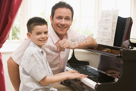 弹钢琴和微笑的男人和小男孩