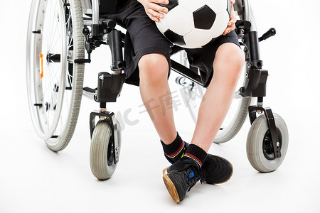 坐在轮椅上拿着足球的残疾儿童男孩