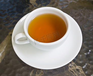 中草药茶摄影照片_玻璃桌上的一杯茶