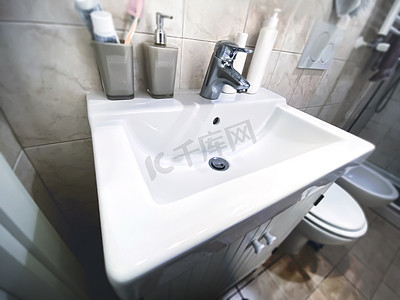 公寓小浴室内带镀铬钢水龙头的白色水槽。