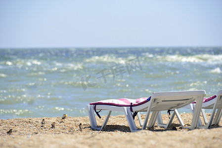 海边活动摄影照片_沙滩上靠近海边的日光浴床
