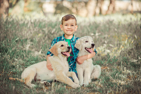 小狗尾巴摄影照片_可爱帅气的蓝眼睛男孩在户外玩耍，带着令人惊叹的白色粉红色拉布拉多猎犬小狗，享受夏日阳光明媚的假期周末，充满快乐。快乐的微笑孩子和最好的朋友