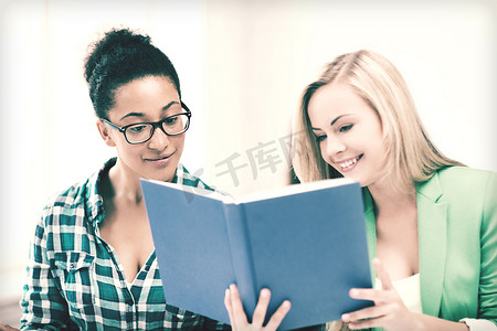 在教室看书摄影照片_微笑的女学生在学校看书