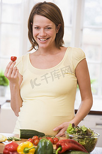 孕妇在厨房里微笑着做沙拉