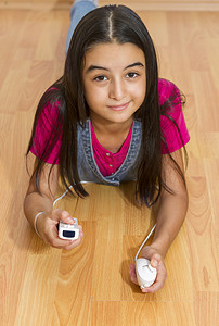 紧身牛仔裤摄影照片_年轻的少女用任天堂 Wii 控制器（游戏手柄）玩电子游戏。