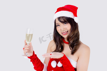 喝饮料女孩摄影照片_美丽的肖像年轻亚洲女人在圣诞老人拿着一杯香槟与派对庆祝圣诞节假期隔离在白色背景，亚洲女孩喝饮料，圣诞节和新年概念。