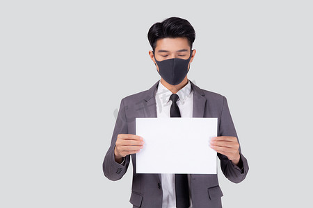 抗疫口号摄影照片_戴着面罩的年轻亚洲商人画像展示了白色背景中孤立的纸片、因 covid-19 危机而失业的商人、covid 的经济和流行病、检疫和口号。