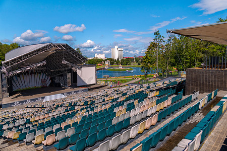 露天的摄影照片_露天的夏季音乐厅，空荡荡的看台，背景是带湖的绿色公园区