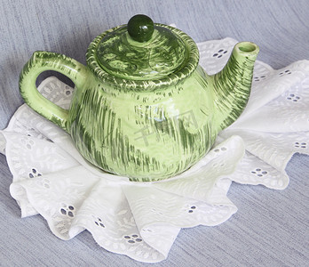 花边餐巾上的绿色茶壶