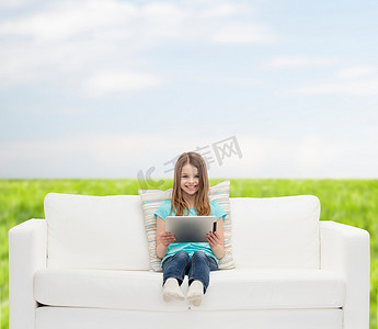 浏览摄影照片_坐在沙发上拿着平板电脑的小女孩