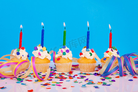 带蜡烛彩带和彩色纸屑的生日纸杯蛋糕