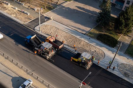 KYIV, UKRAINE - September 10, 2020：带有重型振动压路机的重型沥青压路机在街道上的道路施工现场压上新的热沥青和沥青摊铺机。