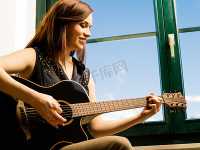 弹窗摄影照片_微笑的女人在窗边弹吉他