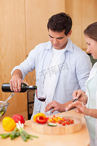一个男人在妻子做饭时倒一杯酒的肖像