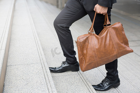 商人带着公文包棕色皮包走上楼，与障碍作斗争爬上成功的完成概念。