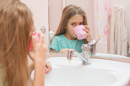 女孩刷牙后漱口，从杯子里拨出嘴里的水