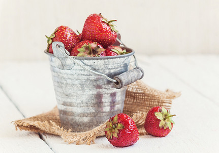 白色背景上旧铁桶中新鲜多汁的草莓
