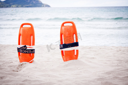 泳救生圈摄影照片_海上物体沙滩上沙子中的橙红色救生圈