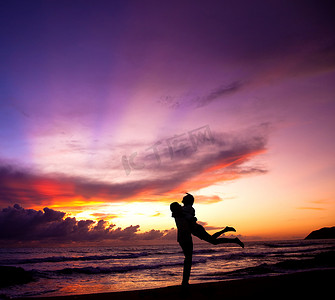 拥抱在海滩的愉快的夫妇剪影