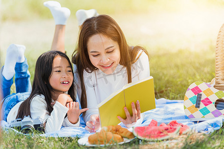快乐的家庭，享受户外的乐趣，躺在野餐毯上看书