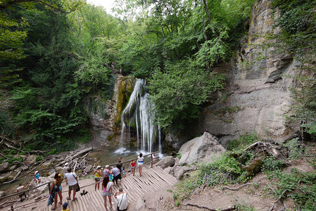 游客们在落基山附近的观景台上观看并拍摄美丽的山瀑布