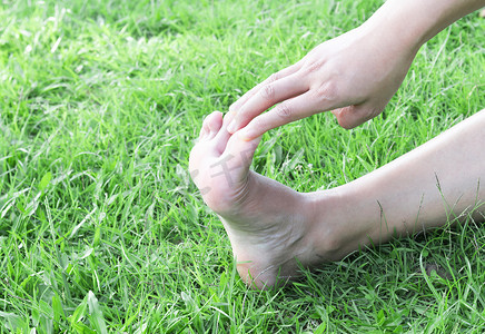 女人在绿草背景上伸展运动脚指