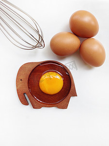 木制大象形碟子上的蛋黄，配鸡蛋和蛋清