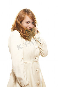 年轻的红头发女人用小鹿色冬衣遮住脸