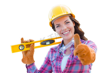 头戴安全帽摄影照片_年轻的女建筑工人竖起大拇指，头戴手套、安全帽和防护镜，与白色隔离。