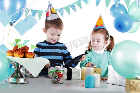 庆贺开幕摄影照片_蓝色派对桌开幕礼物的两个孩子