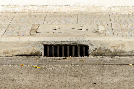 检修孔摄影照片_人行道 0n 混凝土道路下的下水道检修孔。