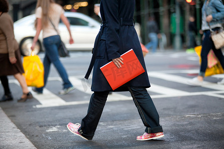 女孩走在大街上，拿着红色的书。