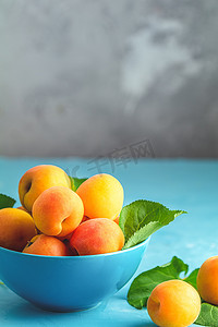 蓝色碗中的新鲜甜橙杏