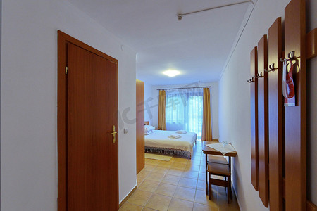 有白色舒展天花板的美丽的宽敞旅馆客房与一张大床和木门。