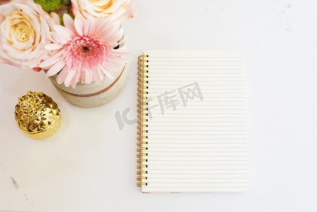 女性工作场所概念采用平躺式风格，配有鲜花、金色菠萝、白色大理石背景的笔记本。