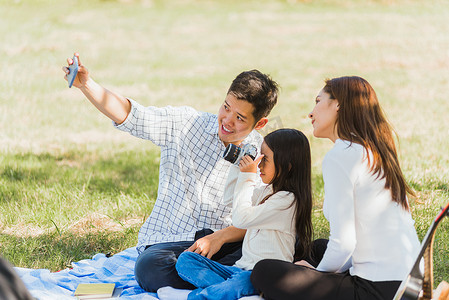 幸福的家庭坐在野餐毯上享受户外乐趣自拍