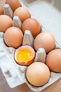 特写镜头破裂的棕色鸡蛋安排在一个纸盒从超级市场购买，把它放在木地板上。