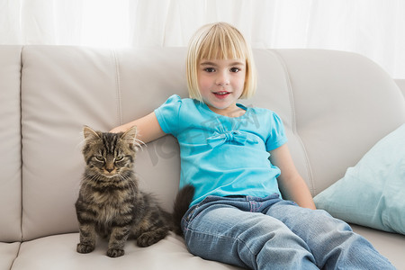 小女孩坐在沙发上抚摸着她的猫