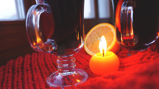 玻璃杯中的甜酒，深红色背景上燃烧的蜡烛。