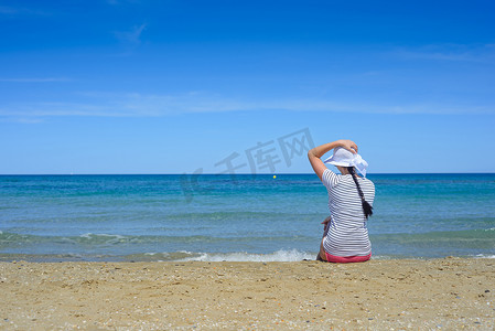 坐在沙滩上望向大海的年轻女子