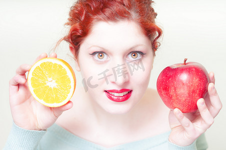 漂亮的红头发和嘴唇的女孩，带着橙子和苹果
