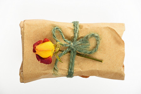 带黄麻弓和白色玫瑰的纸包礼物