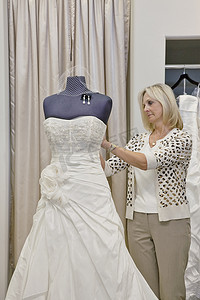 高级女老板在婚纱店调整人体模型上的婚纱