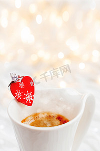 爱情装饰摄影照片_一杯带装饰心形和订婚钻戒的热咖啡，象征着爱情和婚姻。
