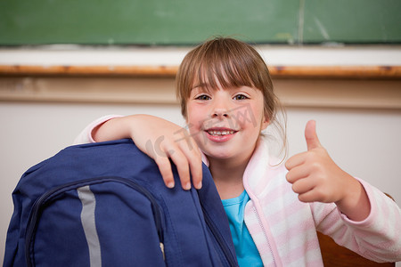 微笑的女学生拿着袋子和大拇指合影