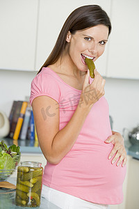 孕妇在厨房里吃泡菜微笑