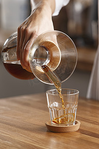 把咖啡倒进木桌上的玻璃杯里